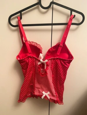 Röd prickig korsett från Soleil Sucré - Snygg röd korsett från Soleil Sucré med vita prickar och spetsdetaljer. Materialet är stretchigt o banden är justerbara! Ca C kupa❣️perfekt till t.ex. fest