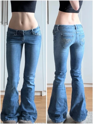 Blå bootcut jeans från World Seurph - Säljer ett par ljusblå bootcut jeans från World Seurph med låg midja. Jeansen har snygga broderade detaljer på bakfickorna och klassisk femficksdesign. Materialet är bomull med lite polyester för extra komfort. Perfekta för dig som gillar retrovibbar och utsvängda ben.