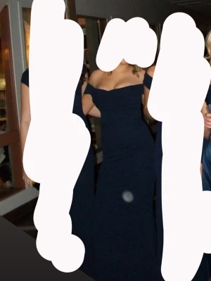 Marinblå offshoulder långklänning - Säljer en elegant marinblå långklänning med offshoulder-design och figurnära passform. Klänningen har en vacker drapering över bysten och är perfekt för bal eller festliga tillfällen. Tyget är mjukt och följsamt, vilket ger en snygg siluett.