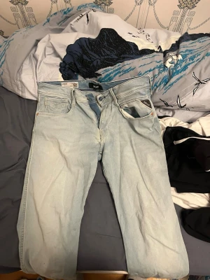 Replay Anbass ljusblå jeans, slim fit - Säljer ett par Replay Anbass Hyperflex jeans i ljusblå tvätt. Slim fit-modell med klassisk femficksdesign, dragkedjegylf och snygga detaljer. Jeansen är tillverkade i stretchigt jeansmaterial för extra komfort och rörelsefrihet. Jag vet inte vad som hände med höger fickan därav pris. Går nog säkert att få bort