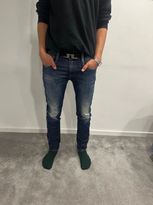 Replay Anbass  - Säljer ett par blå replay jeans med snygga slitningar och tvättade detaljer på låren. Jeansen har klassisk femficksdesign, normal midja och är tillverkade i jeansmaterial. Perfekta för dig som gillar en smal passform och vill ha ett par stilrena jeans till vardags. W30 L32