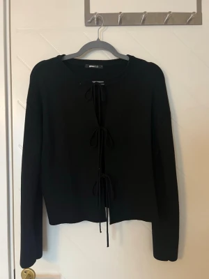 Svart kofta  - Säljer min svarta kofta med knytning fram från Gina Tricot. Tröjan är använd varsamt och nypriset är 400kr men säljer för 100kr. 