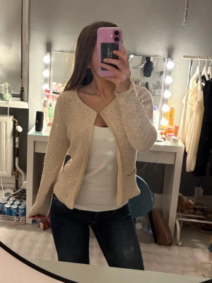 Beige stickad kofta från bondelid  - Säljer en beige stickad kofta från bondelid som har lång ärm och två små fickor framtill. Koftan har en öppen design utan knappar och är i en ljus, neutral ton som passar till mycket. Perfekt att slänga över en topp eller linne för en elegant outfit. Väldigt bekväm och perfekt till en dag då det är både varmt och kallt!❣️