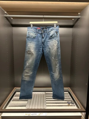 Replay Hyperflex blå jeans straight fit - Säljer ett par Replay Hyperflex jeans i ljusblå tvätt med sopiga slitningar och snyggt slitna detaljer på benen. Klassisk femficksmodell med raka ben och normal passform. Stretchigt material för extra komfort och cool Replay-logga på bakfickan.