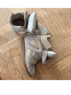 Beige sneakers Isabel Marant mocka - Säljer ett par ikoniska beige sneakers från Isabel Marant i mjuk mocka och skinn. Skorna har chunky design, rund tå, platt gummisula och breda kardborreband. Perfekta för dig som vill ha en cool och trendig look med extra edge.