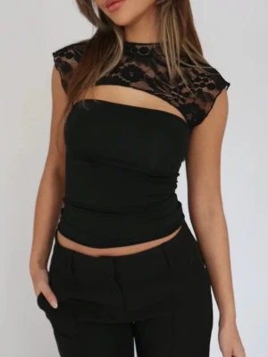 Svart spetstopp från venderbys - Säljer en svart croppad topp med transparent spets upptill och över axlarna. Toppen har en ärmlös bandeau-del under och ett snyggt cut-out parti framtill. Spetsen har blommigt mönster och ger en edgy vibe. Perfekt till höga byxor eller kjol. Venderbys storlek S/M