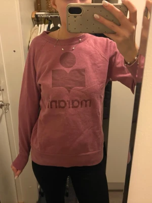 Rosa sweatshirt från Isabel Marant - Säljer en snygg rosa sweatshirt från Isabel Marant med det ikoniska logotrycket framtill. Tröjan har rund halsringning, långa ärmar och ribbade muddar vid ärmslut och nederkant. Perfekt för en chill och trendig look. Har en mindre fläck, se bild. Storlek 40 men som 36.