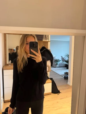 Svart stickad tröja i klassisk modell - En svart stickad tröja med rund hals och långa ärmar. Tröjan har en enkel och tidlös design som passar till det mesta. Mjuk och skön att ha på sig, perfekt för kyligare dagar.