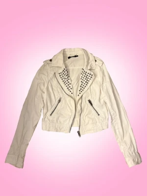 Vit Jeansjacka med Nitar - Cool vit jeans jacka med nitar från GinaTricot. Den är i storlek 38. Den går ner till midjan, så en hyfsat kort jacka. Be aware att den är lite tight vid midjan så den kan vara svår att stänga! 💕  Övrig information: -fraktar torsdagar, fredagar och lördagar -jag står inte för fraktens slarv -priset går alltid att diskuteras via dm -skriv privat för övriga frågor eller om du vill ha fler bilder, svarar snabbt