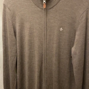 Beige merinoullskofta från Morris - Säljer en stilren beige kofta från Morris i 100% merinoull. Koftan har hel dragkedja framtill, diskret logga på bröstet och långärmad modell. Perfekt för lager-på-lager och snygg till både jeans och chinos. Strl L men passar M. 