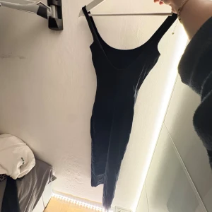 Svart lång tight klänning - En svart långklänning med smala axelband och öppen rygg från beshka.