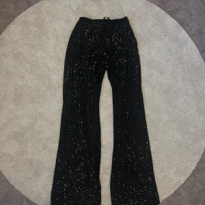 Svarta paljettbyxor från Pull&Bear - Svarta byxor från Pull&Bear, täckta med paljetter, undershorts upptill och lättare genomskinlig resterande av benet. Lägre midja och utsvängda nertill