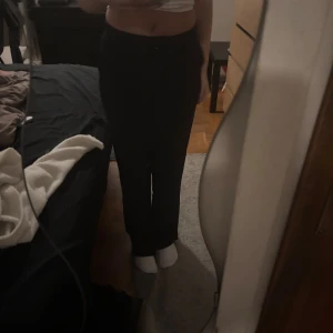 Svarta kostymbyxor från Vila - Svarta kostymbyxor från Vila i klassisk rak modell. Byxorna har medelhög midja och normal passform, perfekta för en clean och stilren look. Materialet är mjukt och följsamt, vilket gör dem bekväma att bära hela dagen. Bara testade. Tveka inte att höra av er vid funderingar💕