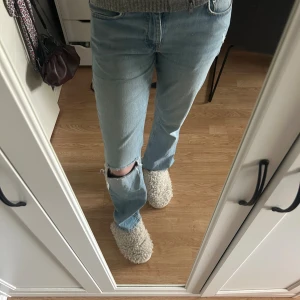 Ljusblå bootcut jeans med hål - Säljer ett par ljusblå jeans med bootcut-modell och snyggt sliten detalj med hål på ena knät. Använda fåtal gånger så dom är i väldigt bra skick🤗🤗💓