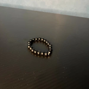 Svart pärlarmband med rundade pärlor - Stilrent svart armband med glansiga, rundade pärlor trädda på elastisk tråd. Perfekt accessoar för dig som gillar minimalistisk och enkel design. Armbandet är diskret men ändå snyggt och passar till många olika stilar.