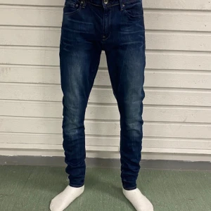 Mörkblå slim jeans från G-Star RAW - W31 L32.  Snygga mörkblå jeans från G-Star RAW med klassisk femficksdesign och diskreta slitningar. Modellen är skinny fit och har en stilren look med mellanblå tvätt. Materialet är en mix av bomull, polyester och elastan för skön stretch och passform.