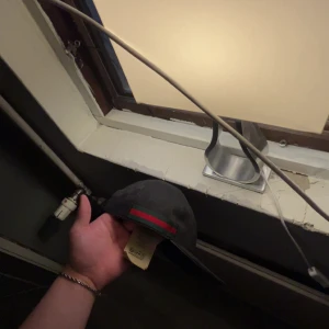 Svart keps från Gucci med röd-grön rand - Säljer en svart keps från Gucci med klassisk röd och grön rand på sidan. Kepsen har diskret GG-mönster i tyget och justerbar rem baktill i skinn. Snygg och stilren accessoar som lyfter din outfit. Pris kan diskuteras vid snabb affär