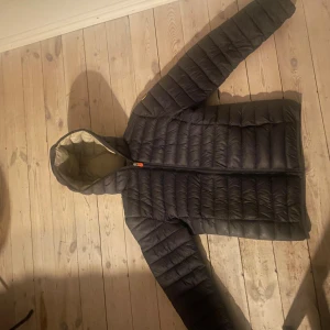 Svart dunjacka från Save The Duck - Tja sälljer denna save the duck jacka. Jackan är i storlek 170 men passar också ungefär xs/s. Jackan har jag använt under en hel vinter, funkar även vid de riktigt kallare vädret men även på tidgia hösten/våren. Jackan är använd men har inga riktigt tydligt synliga defekter. Nypris är ca 1400kr, köpt från zalando  skriv vid frågor kvitto finns
