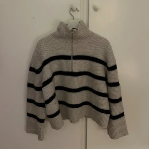 Randig stickad tröja från Weekday - Grå stickad tröja från Weekday med mörkblå horisontella ränder. Tröjan har hög krage, half zip-dragkedja och långa ärmar. Oversized och mysig passform, perfekt för kyliga dagar. Något nopprig men går enkelt att noppra av🩷