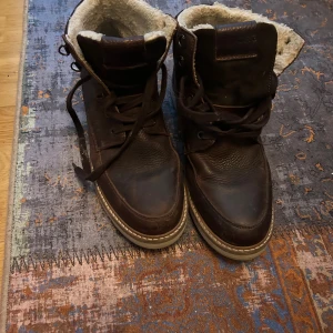 Bruna vinterkängor från Björn Borg - Snygga bruna kängor från Björn Borg med grov sula och snörning. Skorna är fodrade med mjukt, ljust teddyfoder för extra värme. Tillverkade i skinn med robust känsla och detaljer i mörkbrunt. Perfekta för kalla dagar och en stilren vinterlook. Använd ett fåtal gånger mycket fint skick.