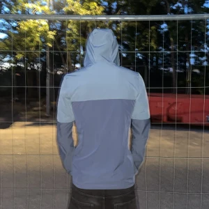 Blå vindjacka från Under Armour - Snygg tvåfärgad blå vindjacka från Under Armour med huva och hel dragkedja framtill. Jackan har en sportig look, reflekterande detaljer på axlarna och logga på bröstet. Perfekt för dig som gillar streetstyle och funktionella plagg.