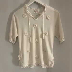 Vit blus med virkade detaljer - Supersöt vit blus med virkade blommor framtill. 