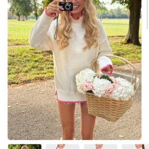 Vit polotröja med rosa detaljer - Supermysig vit polotröja med ribbad hög krage och snygga rosa detaljer vid hals, ärmslut och nederkant. Tröjan är oversized och har långa ärmar, perfekt för lager-på-lager. Mjuk och skön stickad känsla som passar till jeans eller kjol.