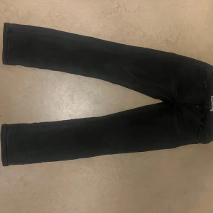 Levi's 512 svarta slim taper jeans - Svarta Levi's 512 jeans med slim taper passform. Klassisk femficksmodell med dragkedja och knapp framtill. Jeansen är tillverkade i ett mjukt denimtyg och har en stilren look som passar till det mesta. Perfekta för dig som gillar en smalare siluett. Lite sliten på jacronen 