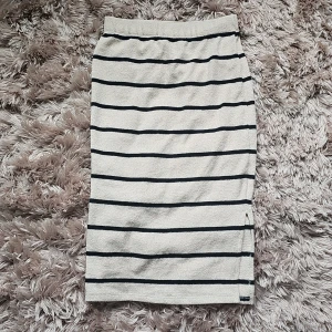 Randig långkjol från Esmara - Beige långkjol från Esmara med svarta horisontella ränder. Kjolen har en liten slits på sidan och är gjord i mjuk, återvunnen polyester med lite stretch. Perfekt för dig som gillar en enkel men snygg look.