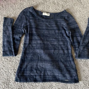 Mörkblå spetsstickad tröja Hollister XS - Supersnygg mörkblå  tröja från Hollister i storlek XS. Det är diskret glitter på tröjan som värkligen är supersnyggt medans baksidan har ett jättefint mönster.tröjna är ganska tunn om de nåt annat ni undrar över kan ni bara fråga .