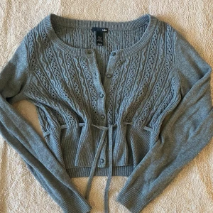 Kofta/ tröja med snörning - Superfin kofta i en mörkgrå färg perfekt för hösten🍂 Justerbar med snöre i midjan så kan passa både S och M! Superfin men kommer tyvärr inte till användning🫶🏼
