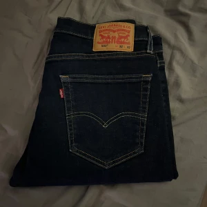 Levi's 502 mörkblå jeans W32 L32 - Mörkblå Levi's 502 jeans med klassisk femficksdesign och snygga kontrastsömmar. Jeansen har en rak passform och är tillverkade i slitstarkt denim med den ikoniska läderpatchen bak i midjan. Perfekta för dig som gillar en tidlös och clean look.