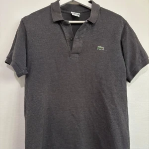 Lacoste piké  - Snygg grå piké från Lacoste i storlek 3, motsvarar medium. 🐊Pikén är i gott skick och har inga defekter.   Vid fler bilder eller frågor är det bara att höra av sig, och kom ihåg, alltid 14 dagars ångerrätt hos oss på Revalo🤝👕