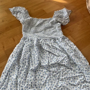 Blommig sommarklänning från KappAhl - Supersöt vit klänning från KappAhl  små blommor och smockad överdel. Puffiga korta ärmar och luftig kjol gör den perfekt för varma dagar. Tillverkad i mjuk bomull. Detta har varit min favorit klänning men nu är den tyvärr för liten😣