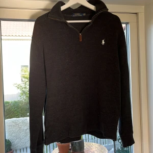 Mörkgrå half zip tröja Polo Ralph Lauren - Mörkgrå långärmad tröja från Polo Ralph Lauren med half zip och klassisk broderad logga på bröstet. Tröjan är iprincip oanvänd med inga tecken på användning .Snygg och enkel att matcha med det mesta. Pris kan diskuteras!