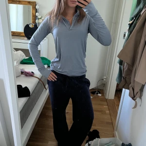 Ljusblå långärmad träningströja half zip - Superskön ljusblå långärmad träningströja med half zip och hög krage. Snygg och enkel design i mjukt, stretchigt syntetmaterial som andas. Perfekt för gymmet eller löprundan, med tumhål i ärmsluten för extra komfort.
