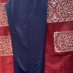 Mörkblå kostymbyxor med pressveck - Snygga mörkblå kostymbyxor med klassiska pressveck längs benen. Byxorna har en rak passform och är perfekta för en stilren look. Tillverkade i ett mjukt material som ger en bekväm känsla hela dagen.