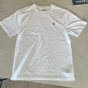 Ralph lauren t-shirt -  Vit t-shirt från Polo Ralph Lauren med broderad marinblå logga på bröstet. Tröjan är helt ny utan prislapp och jag har aldrig använt pga att den är för stor för mig. Kvitto från Kids Brand Store finns fråga mig bara i dm