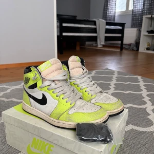 Nike Air Jordan 1 visionaire High OG - Nike Air Jordan 1 Retro High OG i färgen Volt/Black/Sail. Snygga high-top sneakers med vit och voltgul ovandel, svarta detaljer och klassisk svart swoosh. Skorna har snörning, rund tå och platt sula. Materialet är skinn och syntet. Box och extra svarta skosnören medföljer.