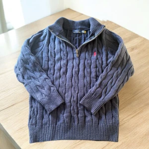 Ralph lauren zip tröja - Polo Ralph Lauren Cable-Knit Tröja med Dragkedja  Skick: mycket bra skick  Storlek: M  Beskrivning:  Erbjuder en exklusiv Polo Ralph Lauren kabelstickad tröja i storlek Large. Denna tidlösa klassiker kombinerar sofistikerad stil med högkvalitativ komfort. Tröjan är tillverkad i en fin kabelstickning och har en praktisk dragkedja vid halsen, vilket ger en mångsidig look. Den ikoniska Polo Ralph Lauren-logotypen är diskret broderad på bröstet.  Detaljer:  *   Material: Högkvalitativt värmehållande