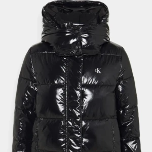 Svart glansig pufferjacka Calvin Klein - Säljer en svart, glansig pufferjacka från Calvin Klein med CK-logga på bröstet. Jackan har hög krage, huva och dragkedja framtill. Perfekt för kalla dagar och ger en cool vibe till din outfit. Den är i storlek m men sitter som s och med vinterjackor rekommenderar jag att köpa en större storlek än vad man brukar ha. Jag brukar ha storlek s och xs i kläder och M funkar för mig när det kommer till jackor. Skriv gärna för mer frågor🤍 köptes för ungefär 2500kr tror jag