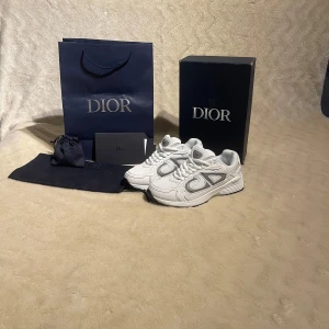 Dior b30 - Säljer ett par snygga vita Dior sneakers med reflekterande detaljer på sidorna och CD-logga bak. Box, kvitto och påse ingår. Pris kan diskuteras 