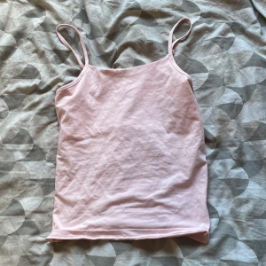 Ljusrosa linnetopp från 157 - Säljer en söt ljusrosa linnetopp från 157 med smala axelband. Toppen är enkel och stilren, perfekt att matcha med jeans eller kjol. Tillverkad i mjuk bomull för en skön känsla hela dagen.