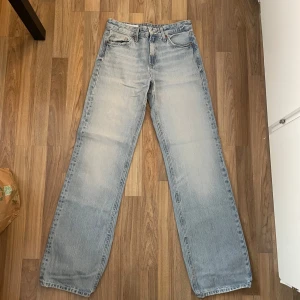 Ljusblå mid waist raka jeans från Zara - Säljer ett par ljusblå jeans från Zara med klassisk femficksdesign och raka ben. Jeansen har en avslappnad passform och är tillverkade i slitstarkt denim. Perfekta för dig som gillar en tidlös och chill stil.
