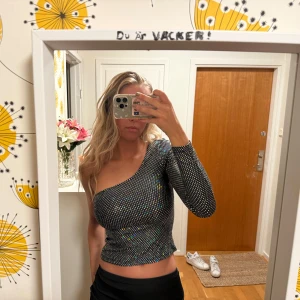 Glittrig topp - Glitter one shoulder topp. Snygg till nyår eller likande. Har tappat glittret i armhålan men syns inte om man inte har uppe armen. Sticks inte eller så.
