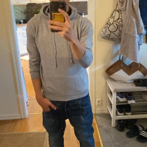 Ljusgrå stickad hoodie  - Säljer en stilren grå hoodie med huva och snörning. Tröjan är helt ny och passar perfekt 150-160