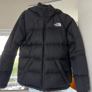 Svart pufferjacka från The North Face - Säljer en svart pufferjacka från The North Face med huva och dragkedja framtill. Perfekt nu till kyligare väder! 💕Superfint skick utan defekter eller liknande, endast använd en säsong.