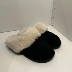 Svarta tofflor med päls - Mysiga svarta uggs liknande tofflor med fluffig päls runt kanten. Perfekta när det är kallt. Aldrig använda!!! 