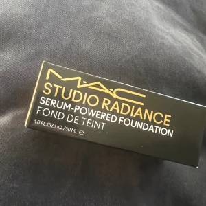 MAC Studio Radiance Foundation N32 - MAC Studio Radiance Serum-Powered Foundation i nyansen N32. Kommer i en snygg svart kartong med guld- och vit text. Innehåller 30 ml flytande foundation som ger en naturlig glow och jämn hudton.