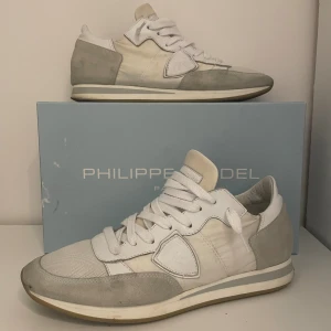 Philippe Model vita och grå sneakers - Snygga sneakers från Philippe Model i vitt och ljusgrått. Skorna har en klassisk låg siluett med rund tå, snörning och detaljer i mocka och skinn. Fråga gärna om ni undrar nåt och priset är inte hugget i sten🙌